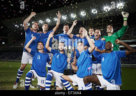 Squadra di calcio tifo con trofeo su campo Foto Stock