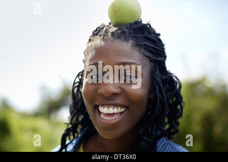 Una giovane donna con una mela verde sulla cima della sua testa Foto Stock