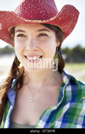 Una giovane donna con trecce in una vasta rosa-colmato cappello di paglia Foto Stock