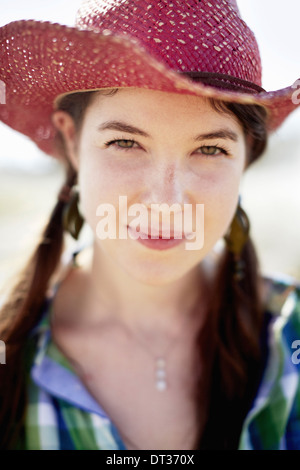 Una giovane donna in denim camicia e stivali su il cofano di un trattore Foto Stock