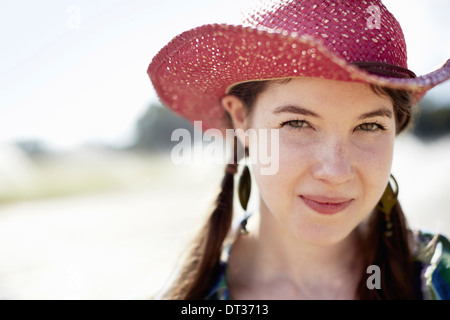 Una giovane donna in denim camicia e stivali su il cofano di un trattore Foto Stock