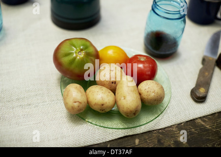 Una tabella con un panno e la piastra con patate e pomodori Foto Stock