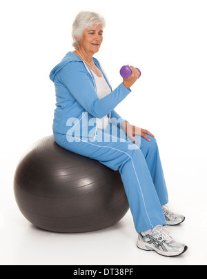 Lunghezza completa studio foto di donna matura seduti sul saldo-ball il sollevamento di pesi su sfondo bianco. Foto Stock