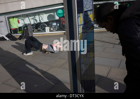 Un giovane guidatore di skateboard risiede nel dolore dopo volare in aria e lo sbarco pesantemente dopo un salto acrobatico passi verso il basso. Foto Stock