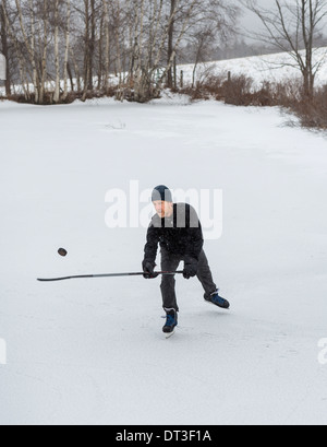 WARREN, Vermont, USA - Uomo pattinaggio sul laghetto congelato, hockey, giocoleria puck. Foto Stock