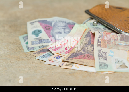 Bollette colorate dal Guatemala e Belize fuoriusciti da un sacchetto di cuoio su un bancone Foto Stock