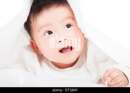 Carino baby sorridente sotto una coltre bianca o asciugamano su bianco Foto Stock