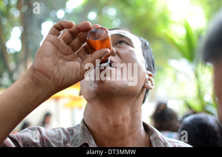 Un uomo di bere liquore tradizionale chiamato Badek in un rituale pellegrinaggio presso la tomba di Prabu Anom Doko nel villaggio. Foto Stock