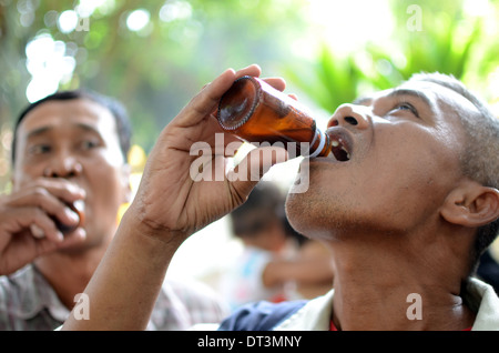 Un uomo di bere liquore tradizionale chiamato Badek in un rituale pellegrinaggio presso la tomba di Prabu Anom nel villaggio Doko Foto Stock