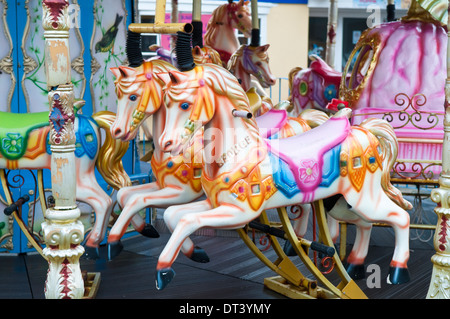 Dipinto luminosamente cavalli in legno su un tradizionale vecchio fiera carosello ride Foto Stock