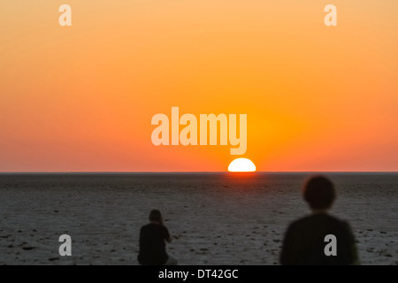 I turisti a guardare e a fotografare il tramonto a Chott El Jerid, un grande lago di acqua salata nel sud della Tunisia. Foto Stock