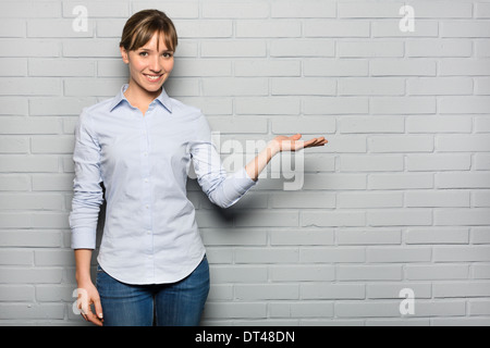 Femmina allegro Grazioso monolocale di puntamento sfondo grigio Foto Stock