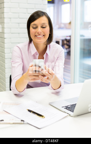 Femmina cella di business desk telefonico digitando Foto Stock