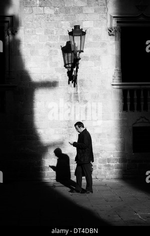 Business man controlla il telefono in presenza di luce solare street. Foto Stock