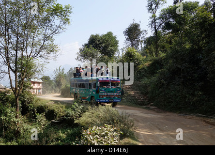 Passeggeri a cavallo sul tetto di un autobus nella regione di Gorkha del Nepal. Foto Stock