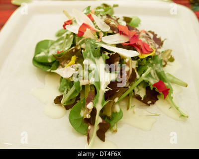 Elegante Insalata mista con foglie di lattuga, fiori commestibili e un latticello ranch dressing Foto Stock