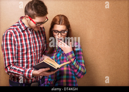 Coppia giovane in abiti eleganti e hipster gli occhiali per leggere un libro. studio shot