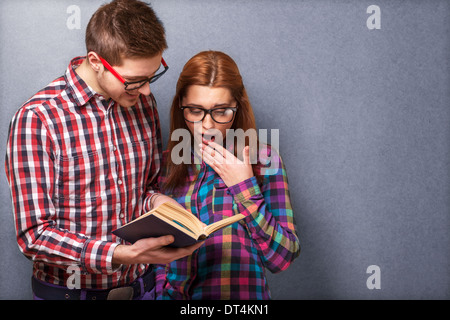Coppia giovane in abiti eleganti e hipster gli occhiali per leggere un libro. studio shot