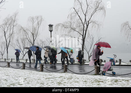 Hangzhou, cinese della Provincia di Zhejiang. Il 9 febbraio, 2014. La gente a piedi sulla coperta di neve Baidi causeway vicino al West Lake in Hangzhou, a est della capitale cinese della Provincia di Zhejiang, Febbraio 9, 2014. Hangzhou ha salutato la prima neve di questo inverno, domenica che era destinato a durare fino a lunedì mattina. © Ju Huanzong/Xinhua/Alamy Live News Foto Stock