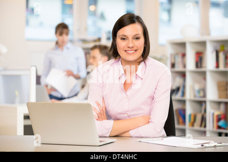 Carino femmina laptop desk colleghi sorridente Foto Stock