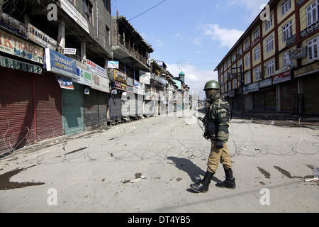 Srinagar Kashmir, India - poliziotti di guardia vicino al filo spinato durante un coprifuoco sommerso a Srinagar, la capitale estiva del Kashmir indiano 09 febbraio 2014. Leader separatista Muhammad Yasin Malik fu arrestato qui Domenica come egli era tenuto fuori un corteo di protesta per il primo anniversario del dicembre 2001 Parlamento indiano Attack convict Afzal Guru appeso, forze di sicurezza indiane hanno imposto restrizioni nelle parti di Srinagar città e in alcune altre città importanti della valle del Kashmir per mantenere la legge e l'ordine. Foto: Altaf Zargar/DPA Foto Stock