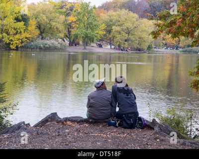 Due persone di godere di alcuni caldo autunno Meteo lungo il lago in Prospect Park di Brooklyn, New York. Foto Stock