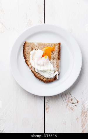 La prima colazione con uovo in camicia e pane bianco su sfondo di legno Foto Stock