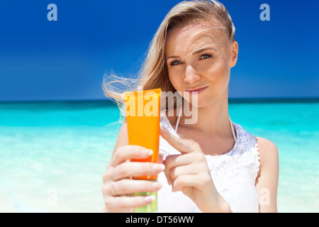Ritratto di donna azienda crema di protezione solare sulla spiaggia, il concetto di bellezza Foto Stock