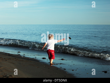 Piccolo ragazzo giocando con pietre su una spiaggia Foto Stock