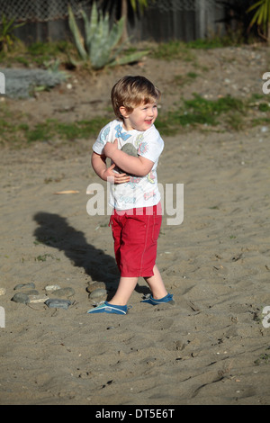 Piccolo ragazzo giocando con pietre su una spiaggia Foto Stock