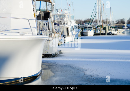 Motore e barche a vela congelati in come Annapolis Harbour ricoperto di ghiaccio. Foto Stock