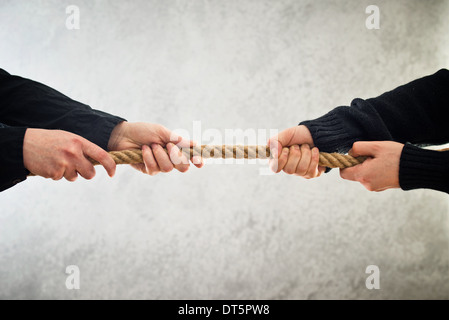 Mani femminili tirando la corda di lati opposti. Concetto di rivalità. Foto Stock