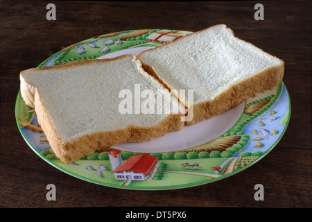 Due pezzi di pane, recante su di una piastra. Prima immagine di una serie sulla creazione di un burro di arachidi e gelatina sandwich. Foto Stock