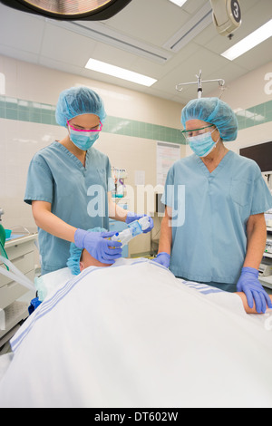 Gli infermieri regolando le maschere di ossigeno su paziente Foto Stock