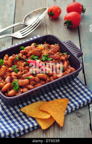 Chili con carne in cottura stampo con tortilla chips su sfondo di legno Foto Stock