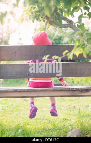 Tranquilla estate scena. Giovane ragazza seduta da sola in giardino, la visione di piante e fiori. Foto Stock