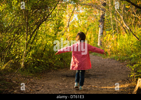 Felice toddler femmina passeggiando attraverso il bosco in autunno Foto Stock