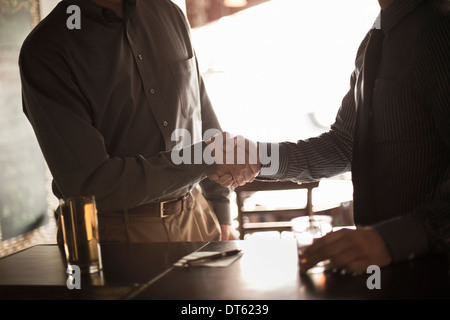 Due imprenditori stringono le mani in wine bar Foto Stock