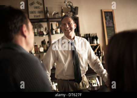 Il barista in chat con i clienti in wine bar Foto Stock