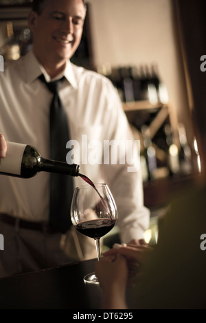 Barista versando il vino rosso in bar Foto Stock