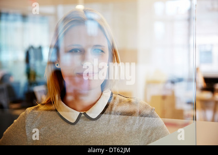 Vista attraverso il vetro della femmina di lavoratore di ufficio Foto Stock