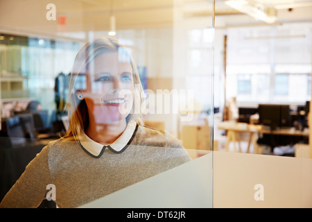 Vista attraverso il vetro della femmina di lavoratore di ufficio Foto Stock