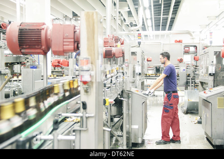 Uomo al lavoro su linea di produzione nella fabbrica di birra Foto Stock