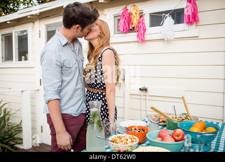 Coppia giovane la condivisione di un bacio in giardino Foto Stock