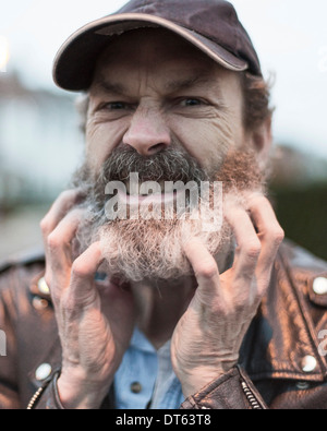 Uomo maturo di graffiare la barba Foto Stock