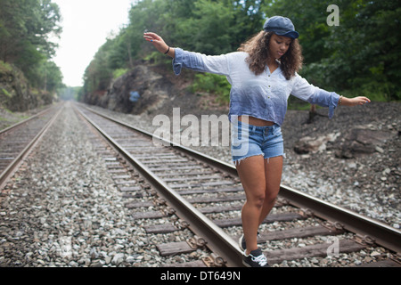 Ragazza adolescente camminando sul binario ferroviario Foto Stock