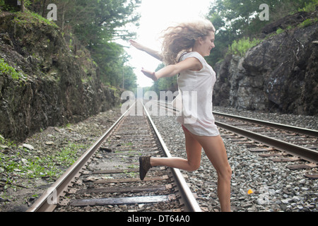 Ragazza adolescente saltando su binario ferroviario Foto Stock