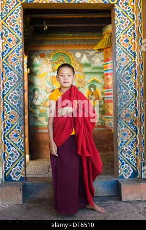 Il Bhutan, Asia del Sud, Punakha, singolo giovane debuttante boy monaco in piedi nella porta di Chimi Lakhang tempio della vecchia capitale. Foto Stock