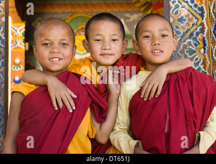 Il Bhutan, Asia del Sud, Punakha, tre giovane debuttante boy monaci in piedi nella porta di Chimi Lakhang tempio della vecchia capitale. Foto Stock