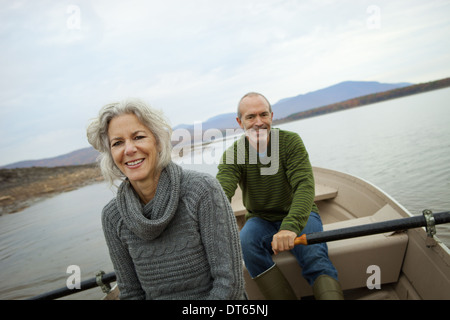 Un giovane uomo e donna seduta in una barca a remi in acqua in una giornata autunnale. Foto Stock